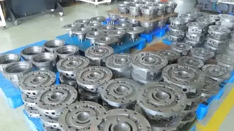 Stacks of machined hydraulic component housings on blue pallets